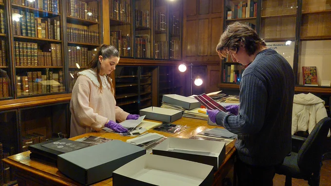 Students Bea Crossley and Eddie James looking at boxes of archival material.  
