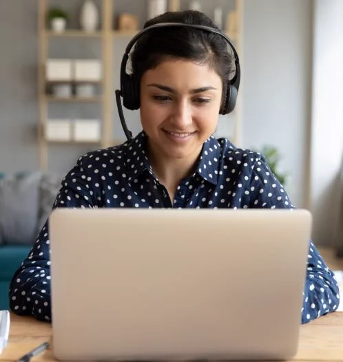 Woman wearing headphones while looking at a laptop