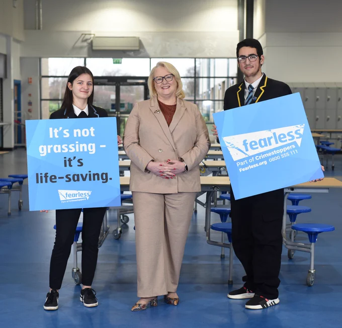 Minister for Drugs & Alcohol Christina McKelvie stands beside two pupils from Craigroyston Community High School. Pupils hold signs that read 'it's not grassing - it's life saving' and 'Fearless.org, part of crimestoppers' 