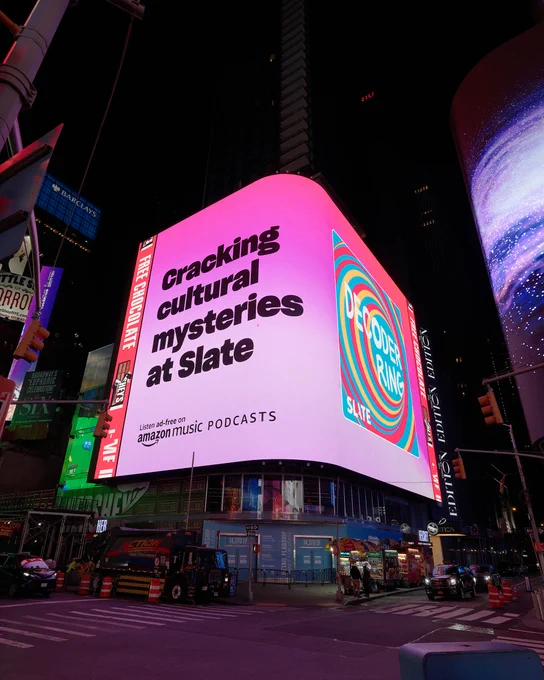 Image of Times Square billboard that reads "Cracking cultural mysteries at Slate" on a pink background with Decoder Ring's cover art to the right.