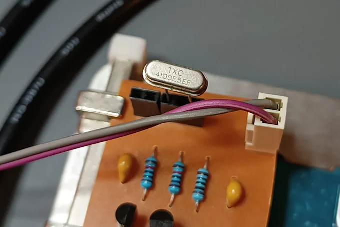 Closeup of a 4 Mhz crystal inserted on a single-row, 5 pin socket on a home-made PCB.