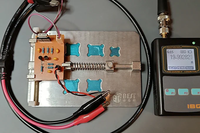 Similar setup; home-made board held by a vice, but this time a 20 Mhz crystal is inserted in the socket. The frequency counter reads 19.993 Mhz