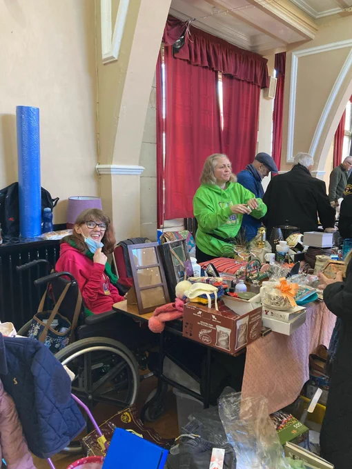 Faye and Sarah at the sale table, lots of items, pottery, picture frames, jewellery, books, clothing.
