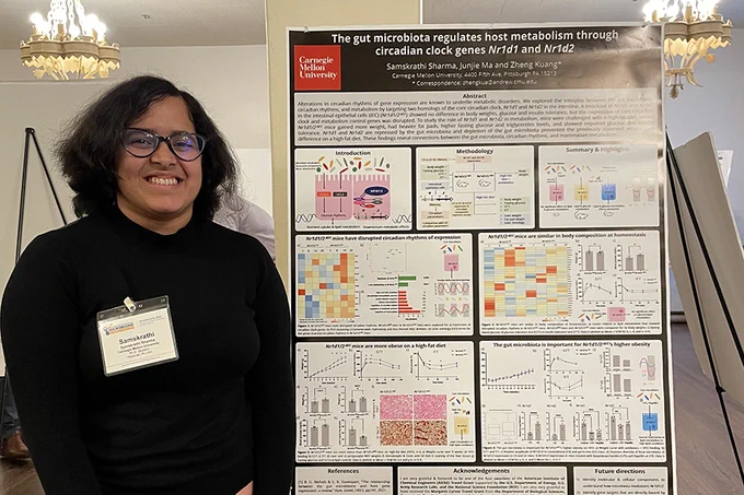 Samskrathi Sharma stands next to a poster on her work. The poster is titled, "The Gut Microbiota Regulates Host Metabolism through Circadian Clock Genes Nr1d1 and Nr1d2."