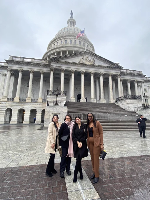 4 individuals standing in front of the US Capitol.
