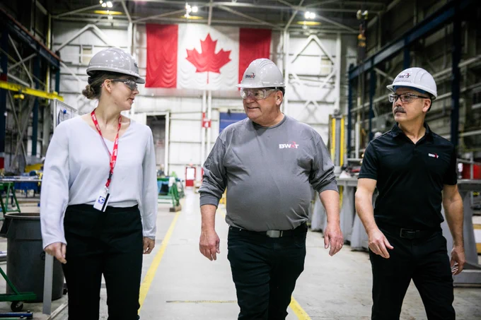Premier Doug Ford and two employees walk through the BWXT facility.