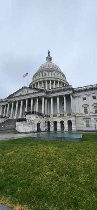 The exterior of the US Capitol building against a gray cloudy sky