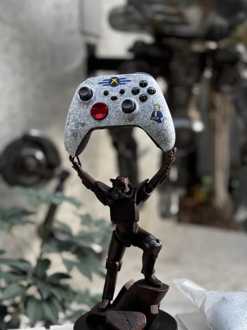 Brotherhood of Steel figurine holding up the Brotherhood version of the Fallout Edition Xbox Wireless Controllers from Xbox Design Labs.