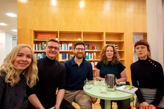 A picture of five panel members sitting down and looking into the camera.
