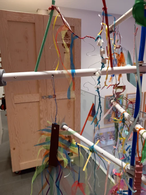 A photograph showing the detail of a structure with hanging paper artworks displayed on it.
