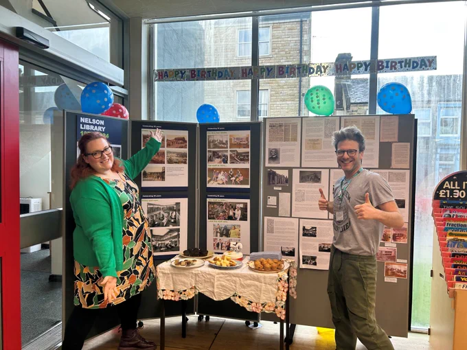 two members of staff in front of a display