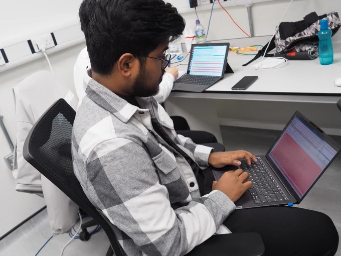 A man is sitting studying some red error messages that have appeared on his laptop screen.