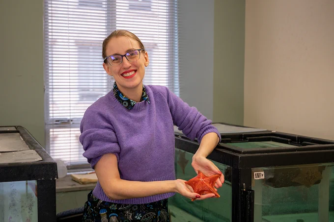 Annie Meyer smiles at the camera while holding a starfish.