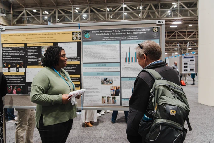 a student discusses her research to an attendee at a conference poster session