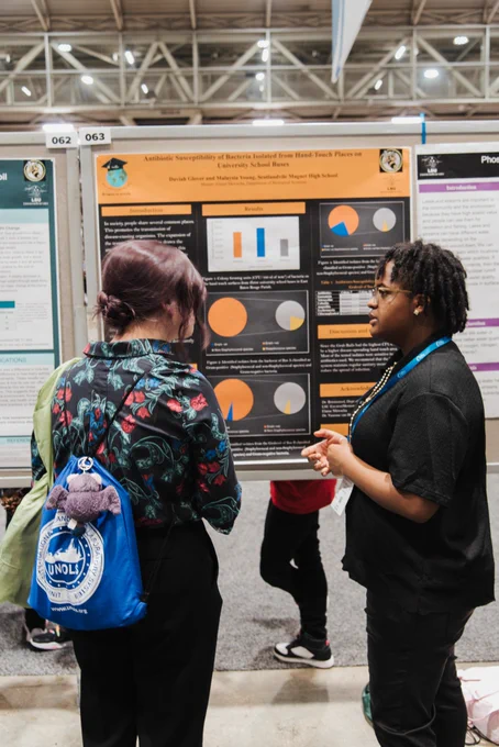 a student discusses her research to an attendee at a conference poster session