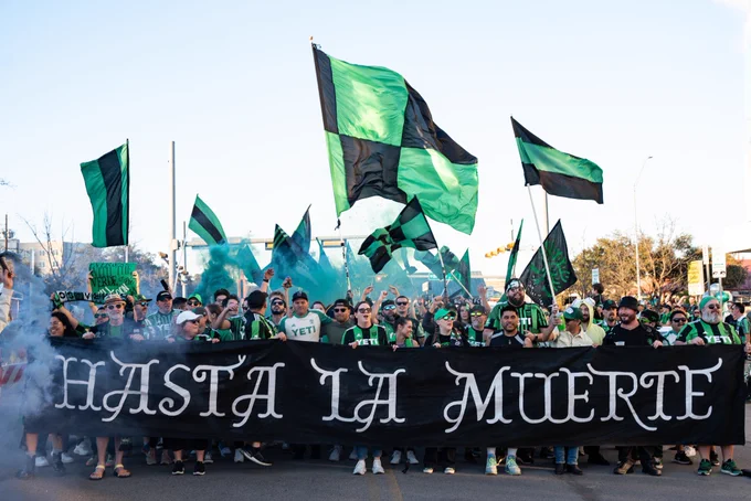 Austin fc fans holding banner saying “Hasta la muerte”