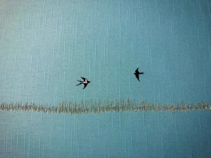 Two tiny embroidery swallows and a gold thread pasture