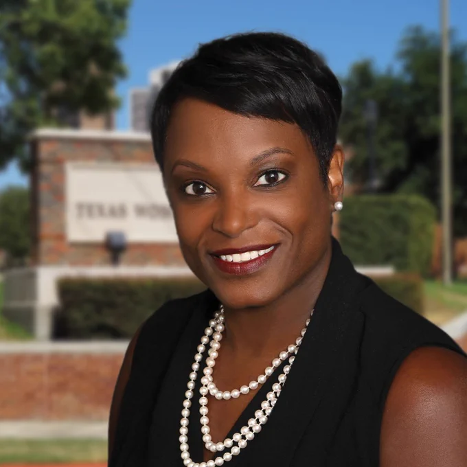 Photo of Dewaynna Horn in front of a sign for Texas Woman’s University
