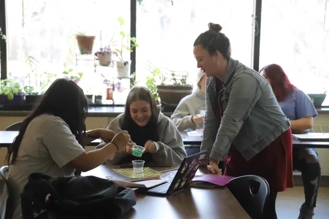 Randi working with some students in her plant-filled classroom.