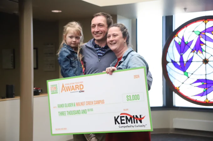 Randi Glaser holding her oversized award check with her husband and young daughter.