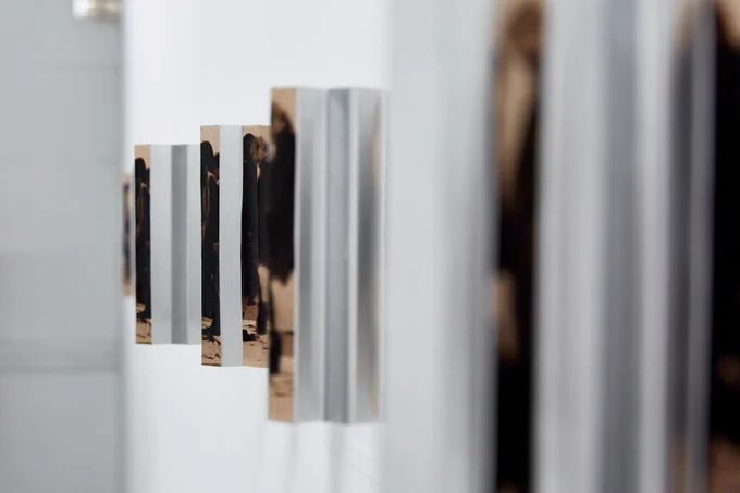 Wall-mounted artwork by Shutong Li, repeating images of standing figures, receding into the distance. 