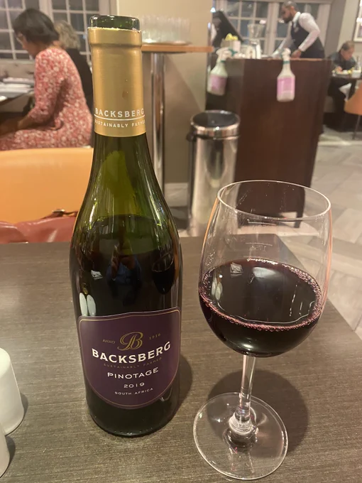 A bottle of Backsberg pinotage wine alongside a glass with some wine in it