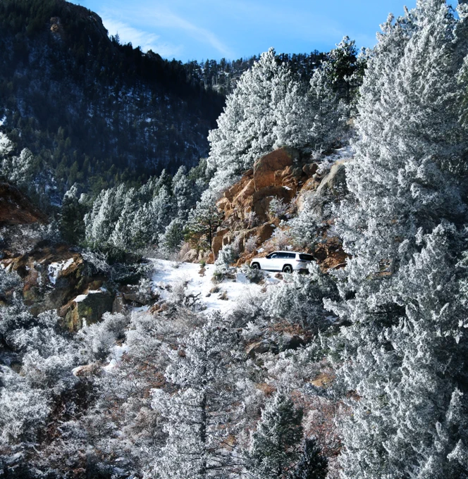 A white SUV drives up the frosty Pikes Peak Highway.