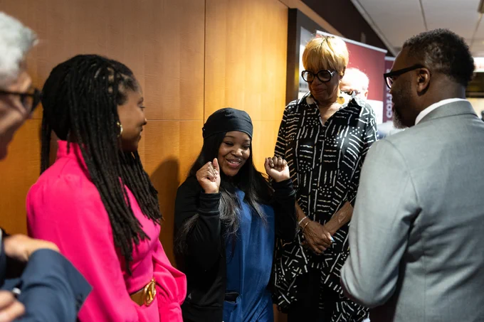 Chicago Mayor Brandon Johnson greets a young Black woman in a hallway.