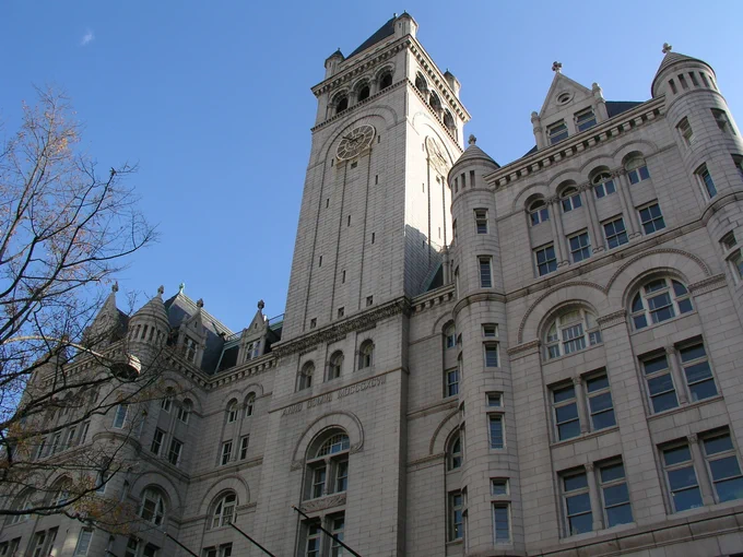 The front exterior of the Old Post Office, a large gray stone building with a clock tower rising in the center.