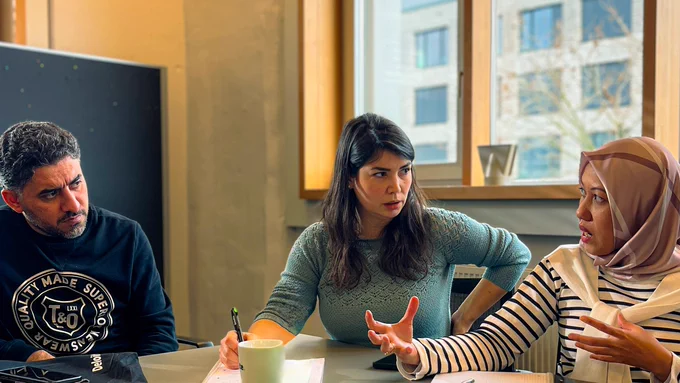 Drei Personen unterhalten sich an einem Tisch über ihren Business Plan