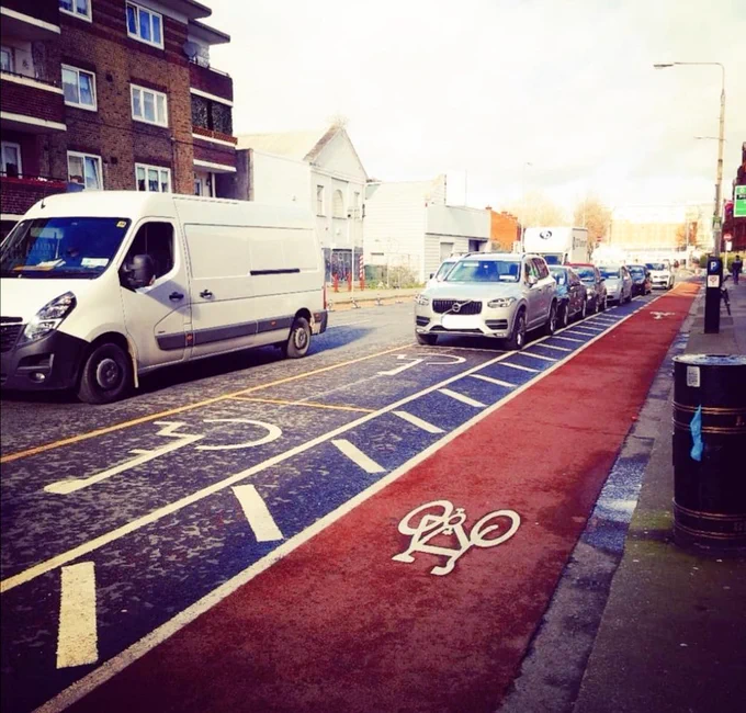 Photo showing 2 vacant disability parking bays realigned away from the path wedged between a busy road on Lombard St (drivers-side) and a cycle lane on passenger side. No dropped kerb access to path. No access aisles. Only a buffer strip to protect cyclists from getting "doored". 