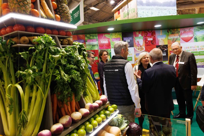 Un rayon de légume figure au premier plan. Derrière, Catherine Vautrin échange avec des membres de l’association Aprifel, dans leur stand au salon de l’agriculture.