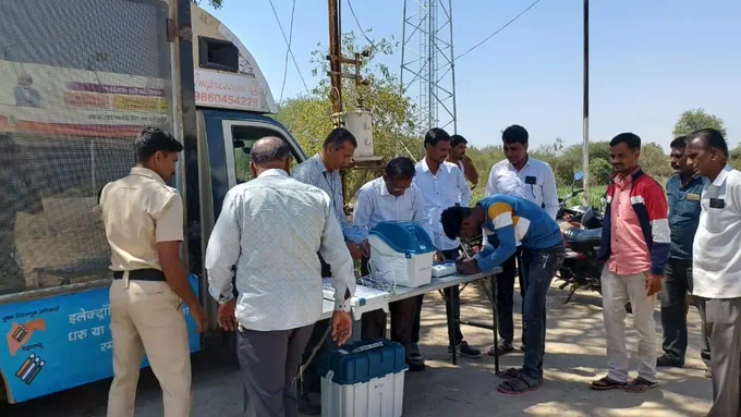 एका ठिकाणी मतदान केंद्रस्तरीय अधिकारी evm मशीन उभे आहे. त्यांच्या मागे evm वाहन उभे आहे त्यावर evm मशीन बद्दल माहितीचे फलक लावले आहे सोबतच वाहन मधील LED स्क्रिन वर मतदार जागृतीपर व्हिडिओ सुरू आहेत. EVM मशीन भोवती जमलेल्या लोकांना मतदान केंद्रस्तरीय अधिकारी मशीन बद्दल माहिती सांगत आहे सोबतच प्रात्याक्षिक सुरू आहे. 