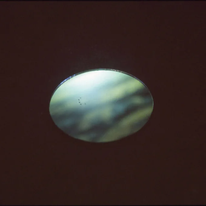 A vague green/blue circle is visible in the centre a dark surface.