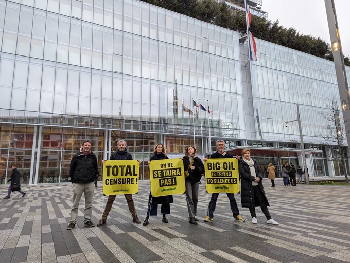 5 militants et militantes de Greenpeace France devant le tribunal de Paris avec des bannières portant les messages : "Total Censure !", "On ne se taira pas !" et "Big oil is trying to silence us"