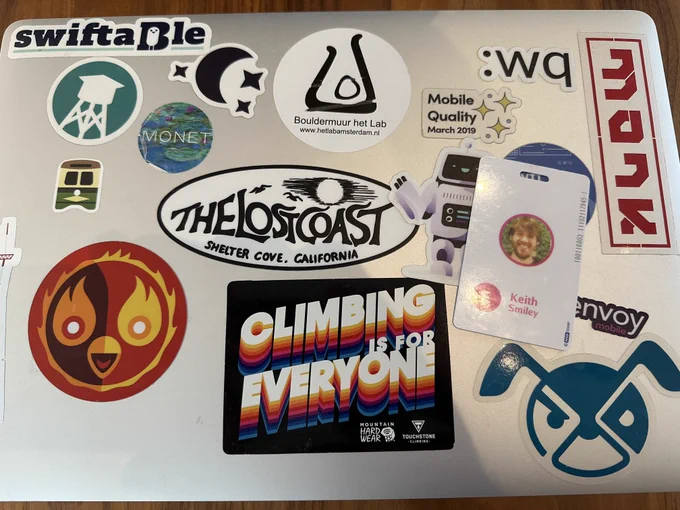 A picture of one of my old Lyft laptops covered in stickers, along with my work badge