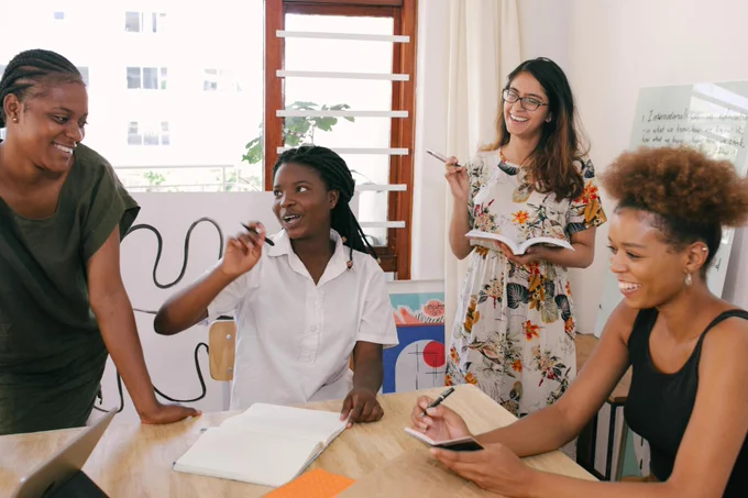 Photo of a diverse group of women talking and smiling around a table.
