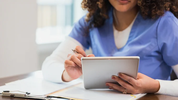 Healthcare worker in uniform reading information on an electronic device. 