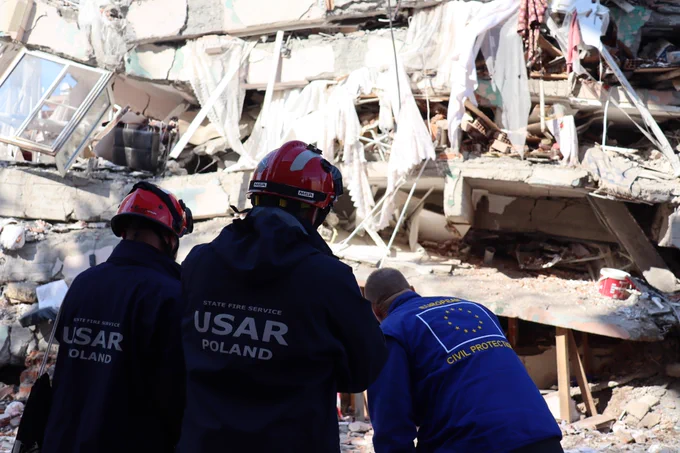 Members of the urban search and rescue team from Poland together with a member of the EU Civil Protection team in front of a building damaged in an earthquake.