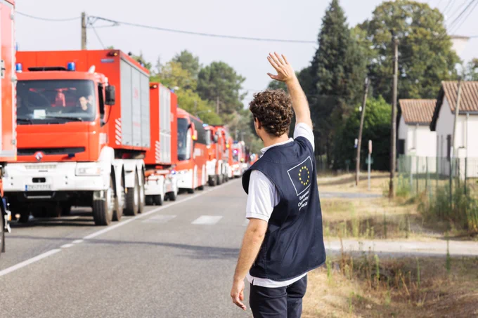 A member of the EU Civil Protection team waving to a passing column of fire engines.