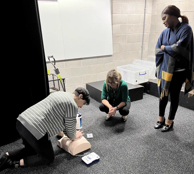 Colleagues taking part in a first aid course with CPR dummy.