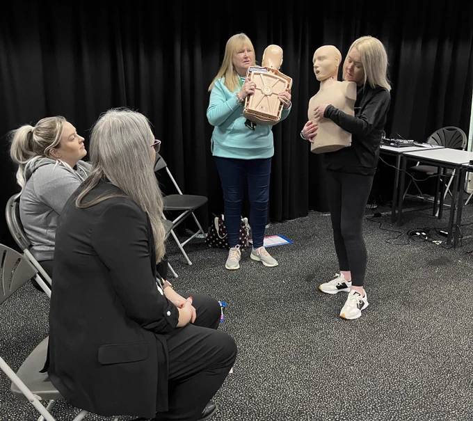 Colleagues taking part in a first aid course with CPR dummy.