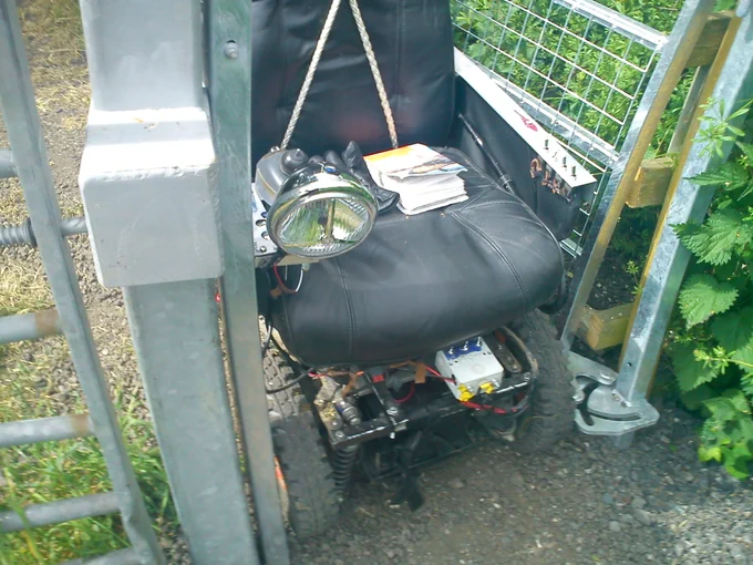 Image shows an electric wheelchair stuck in a narrow gate on a public right of way. The chair in this picture is 640mm wide. The legal minimum clear width of a gate at the time this gate was put in place is 1100mm.