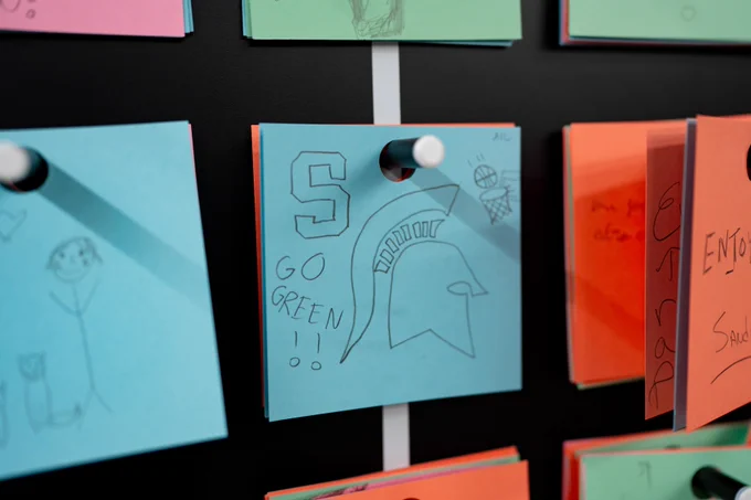 Closeup of a blue post-it note that has a drawing of a Spartan helmet and Go Green written on it
