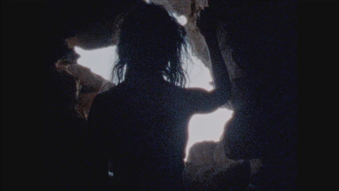 A silhouette of an unidentifiable person looking our of a cave-like enclosure - image from Tomorrow is a Water Palace by Juanita Onzaga, 2022