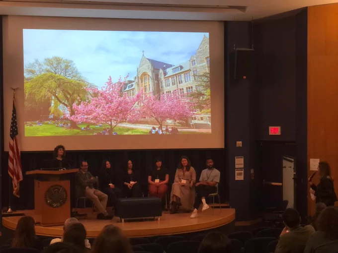 Round table discussion featuring Carmen Perez-Vidal (the moderator), Dr. Christina Isabelli, Dr. Amelia Dietrich, Dr. Jesús Fernández, and Georgetown students Gotanna Andrade, Daniel Stewart, and Leah Metzger. On the right is Dr. Lourdes Ortega asking a question from the audience. 