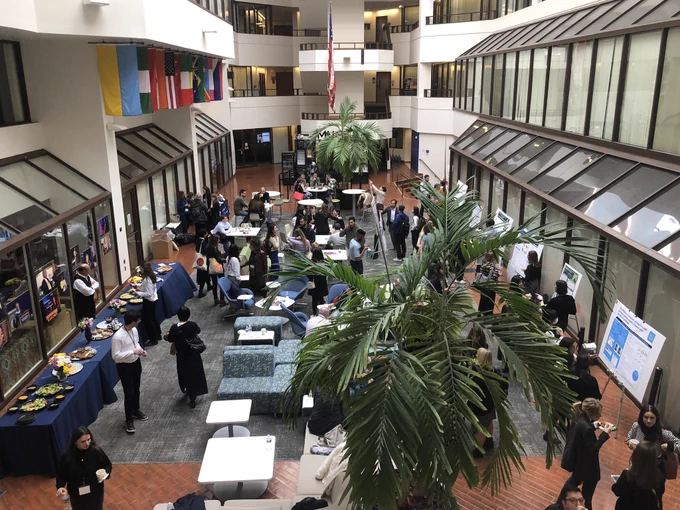 Poster session at the GURT2024 conference. Left side features food while right side showing posters and engagement between presenters and audience.