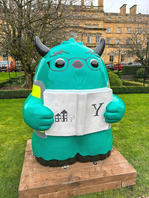 A blue/green Snook holds a York Central branded book with a large letter Y.