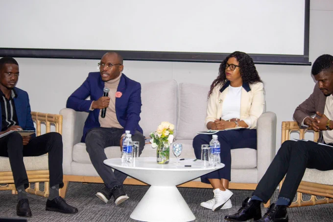 A group of four people sit on a panel on a stage, discussing 