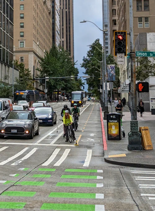 Several people wait at a red light on their bikes along the 4th Ave protected bike lane.